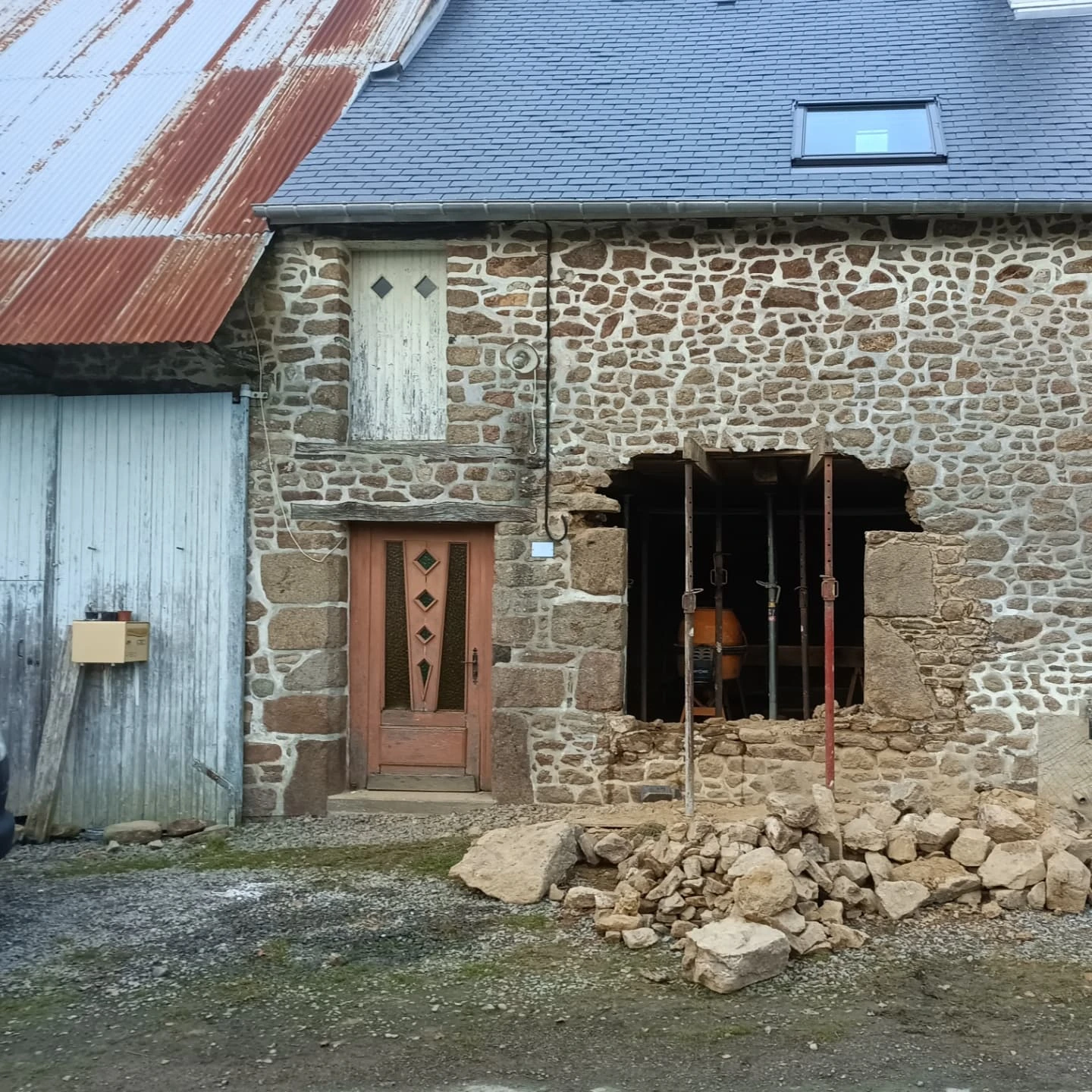 Ouverture en cours, mur étayé et pierres déposées au sol