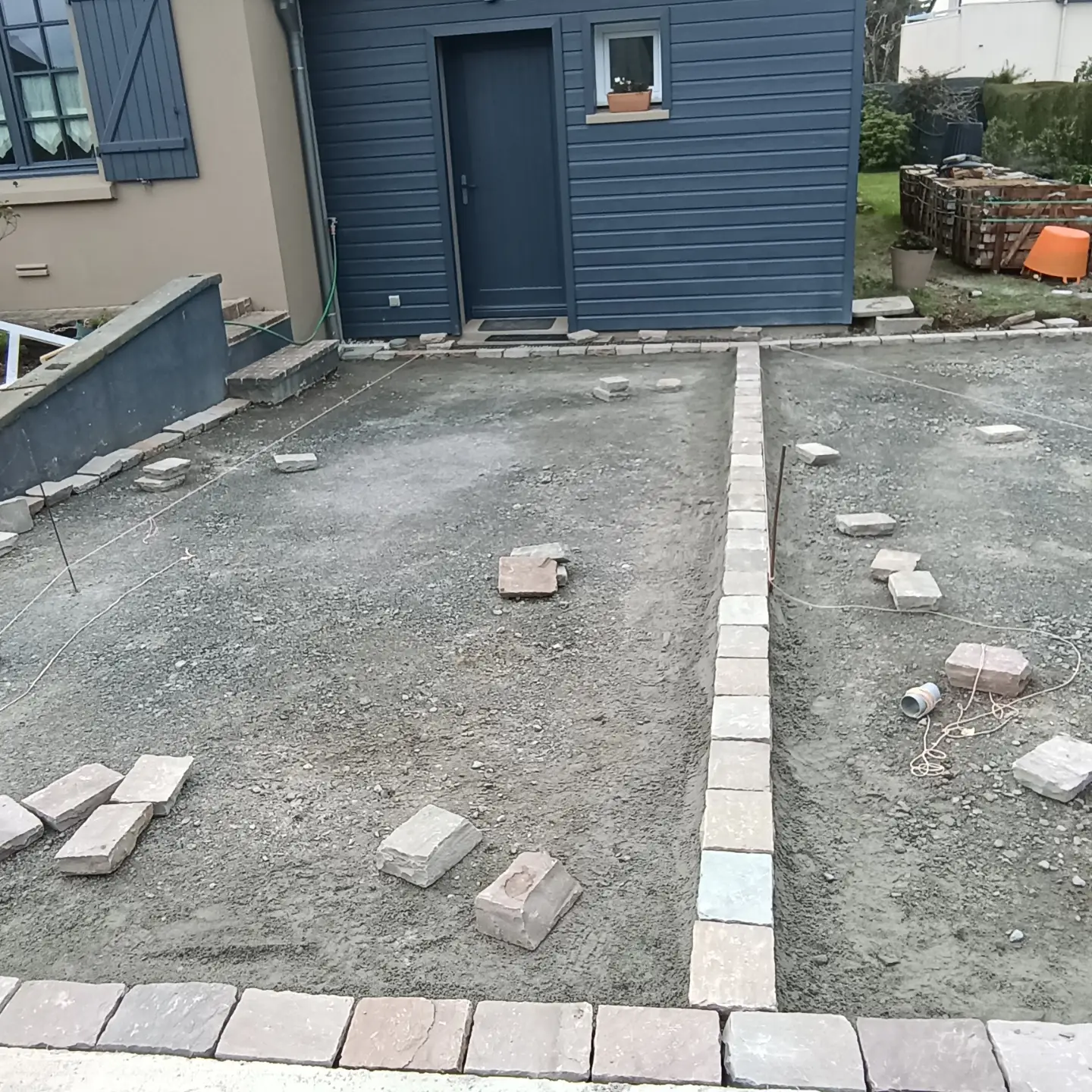 Cour décaissée, lit de pose et bordures en cours d'implantation au cordeau